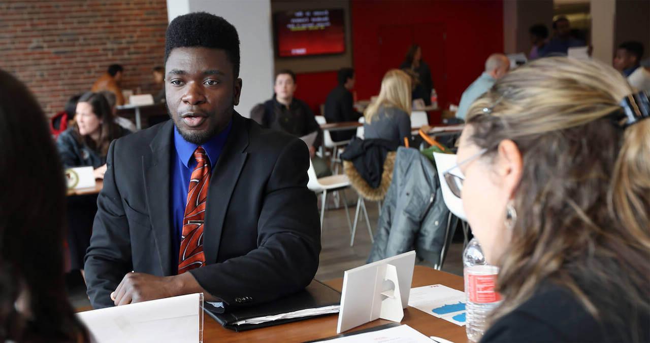 Student at a table talking with employers